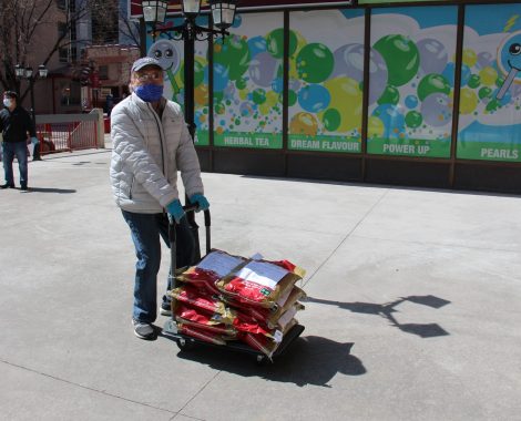 A volunteer wheeling a cart of rice packages across the plaza